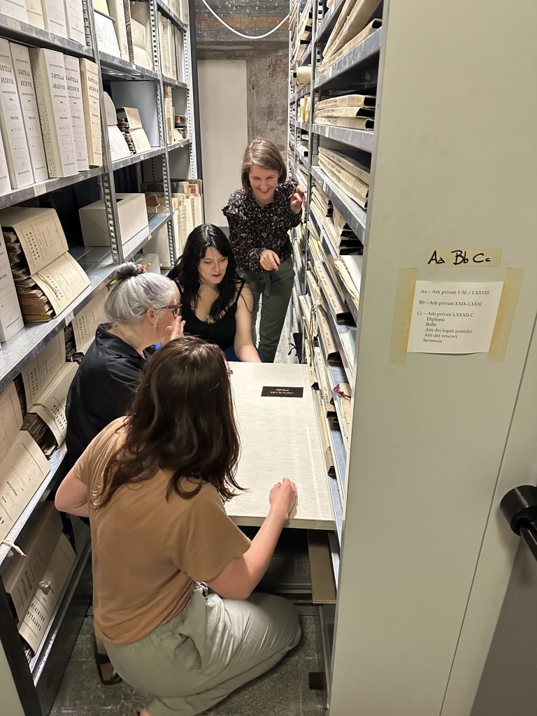 A group of scholars investigate scrolls in the stacks of a medieval archive